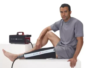 Mężczyzna używający urządzenia Game Ready na kontuzjowane kolano, pokazując zastosowanie terapii zimnem i kompresją w rehabilitacji.