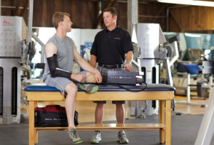 Osoba korzystająca z urządzenia Game Ready do krioterapii miejscowej na kolano podczas rehabilitacji.