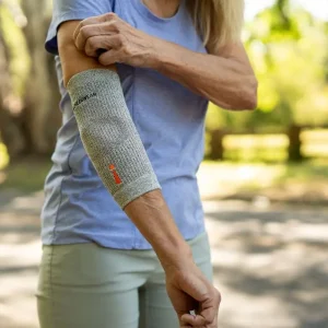 Kobieta zakładająca opaskę terapeutyczną Incrediwear na łokieć