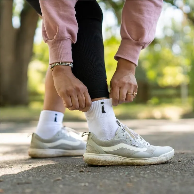 Kobieta poprawiająca białe skarpetki Incrediwear na zewnątrz